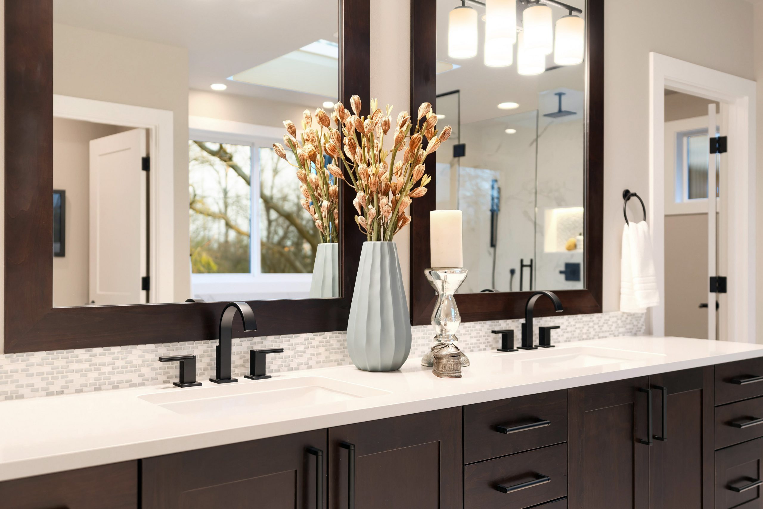Luxury modern home bathroom interior with dark brown cabinets, white marble, walk in shower, free standing tub.
